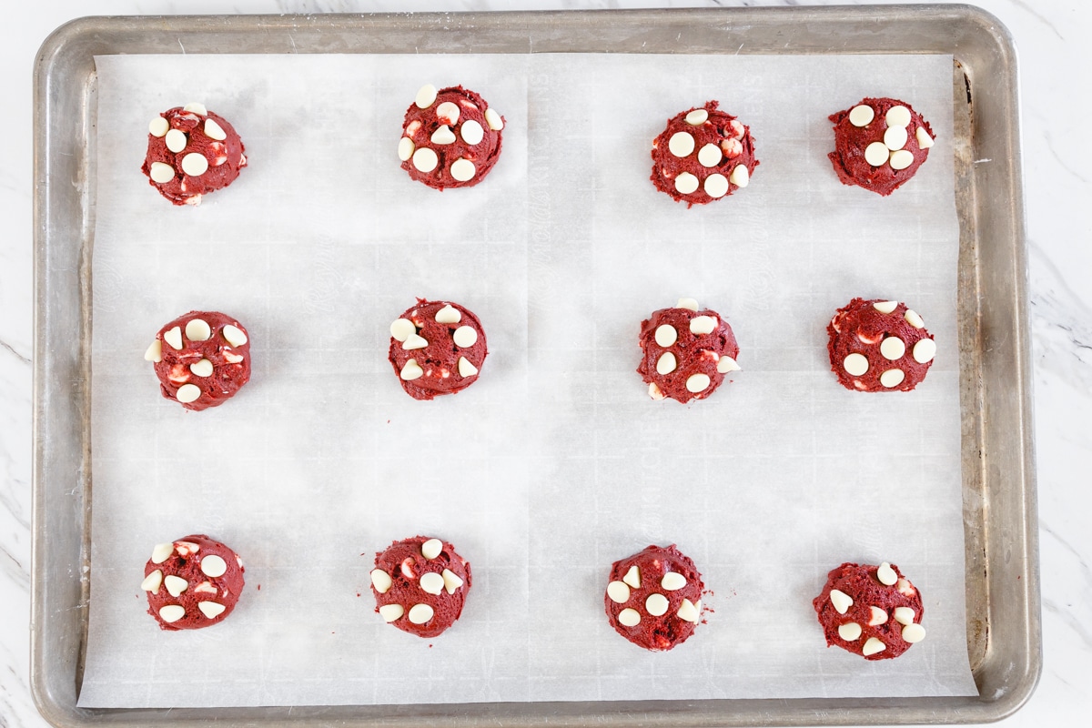 Red Velvet Cookies on baking sheet with white chocolate chips on top