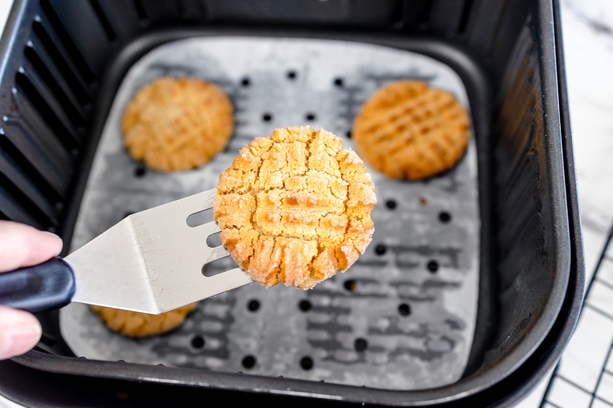 Top view of a fork lifting a cookie out of an air fryer.