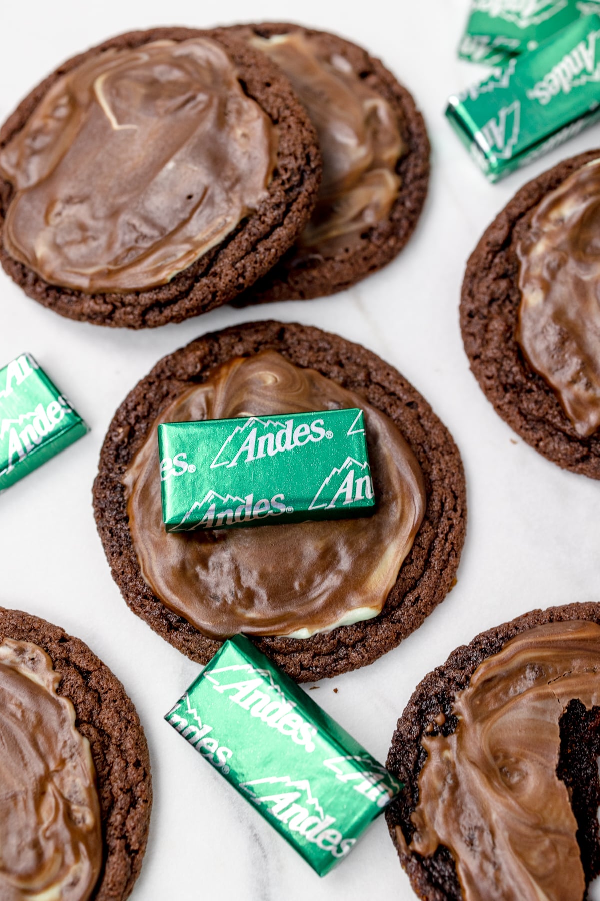 Top view of Andes Mint Cookies on a table with Andes Mints lying on them.