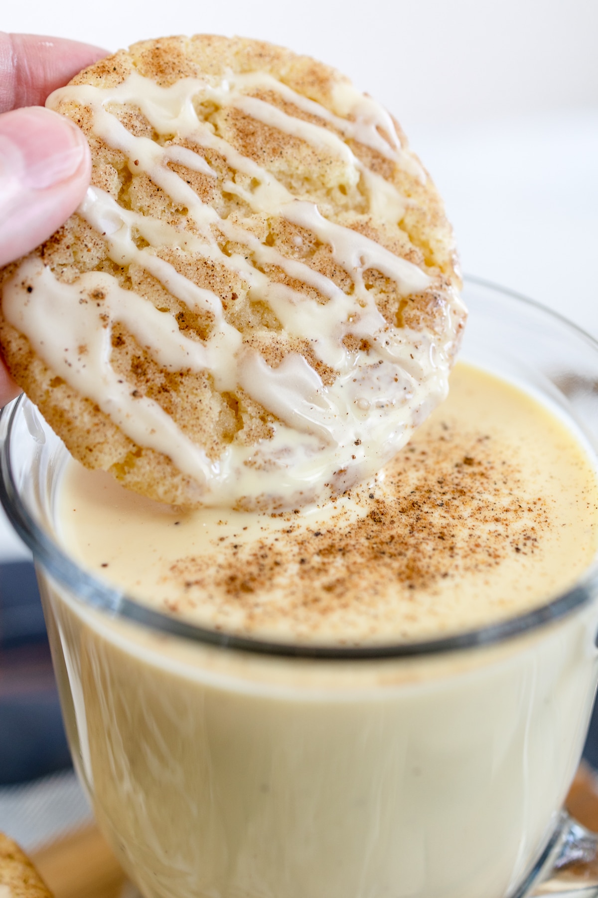 Close up of an eggnog snickerdoodle cookie being dunked into a glass of eggnog.