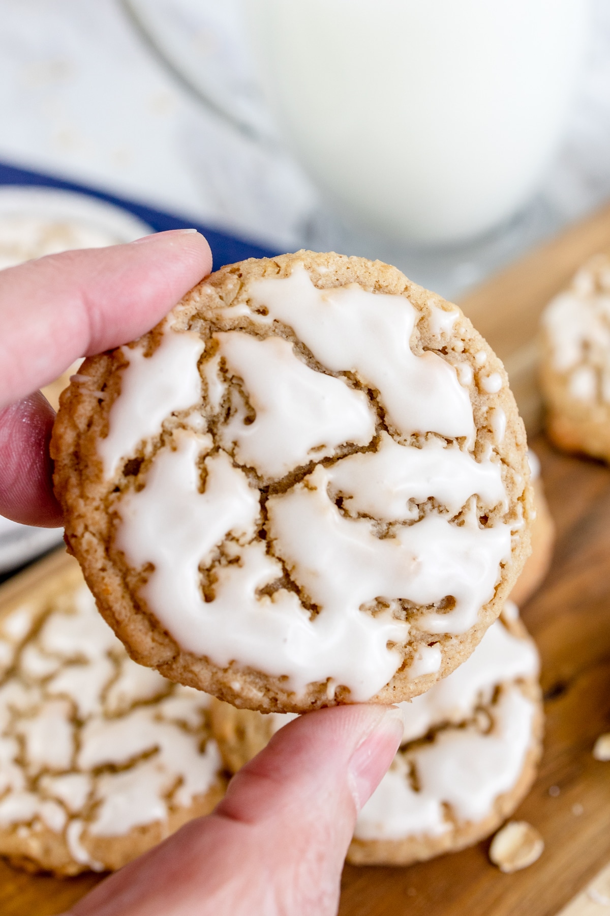 Close up of an Iced Oatmeal Cookie being held up by someone's hand.