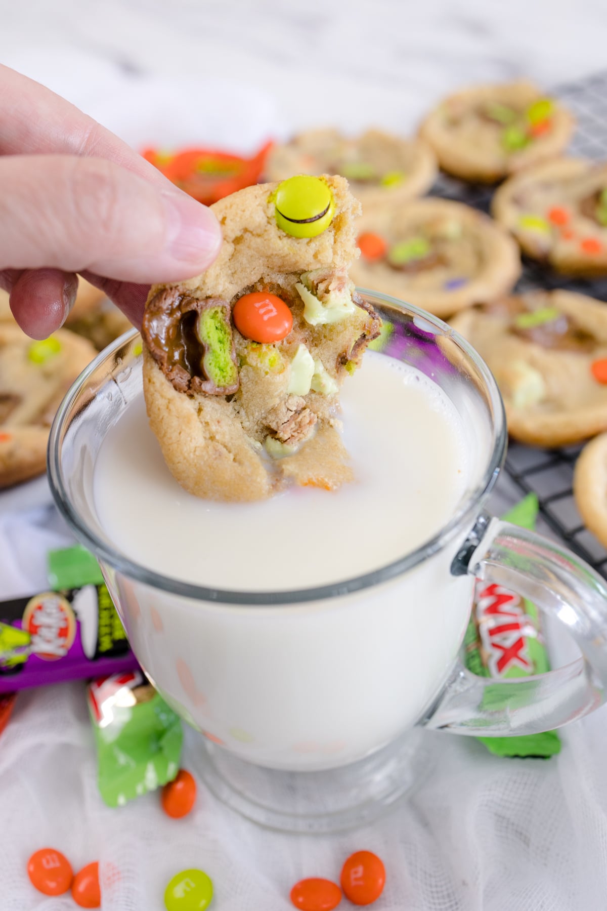 Halloween candy cookie being dunked into a glass of milk.