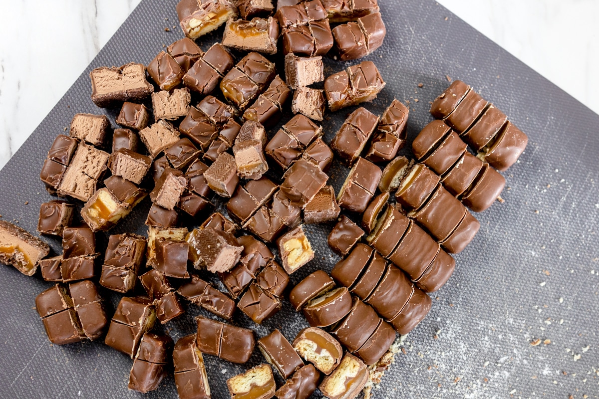 Top view of chopped chocolate bars on a gray chopping board. 
