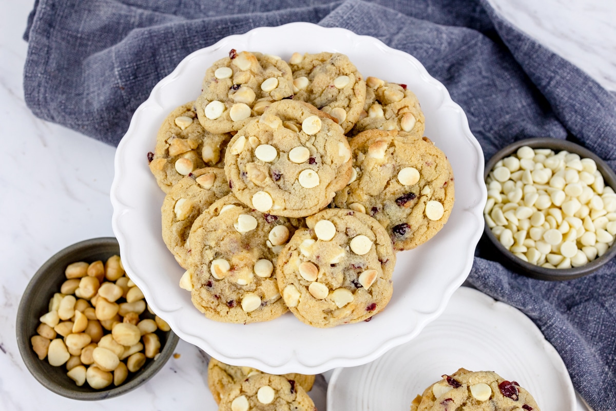 Top view of a plate filled with white chocolate macadamia nut cookies with cranberries.