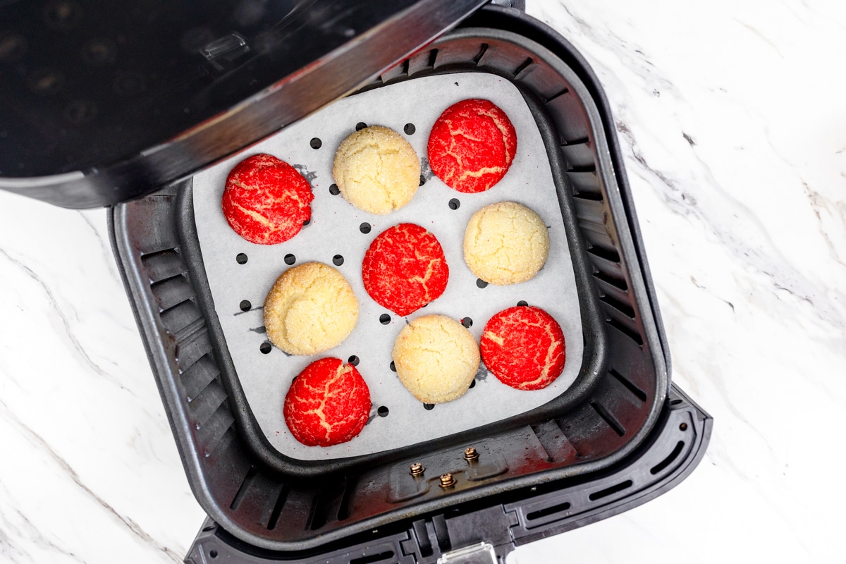 Top view of an air fryer with freshly baked sugar cookies in the bottom.