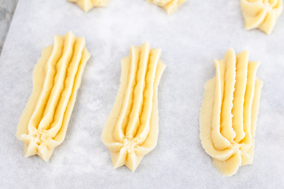 Close up of long stick shapes of butter cookie dough. 