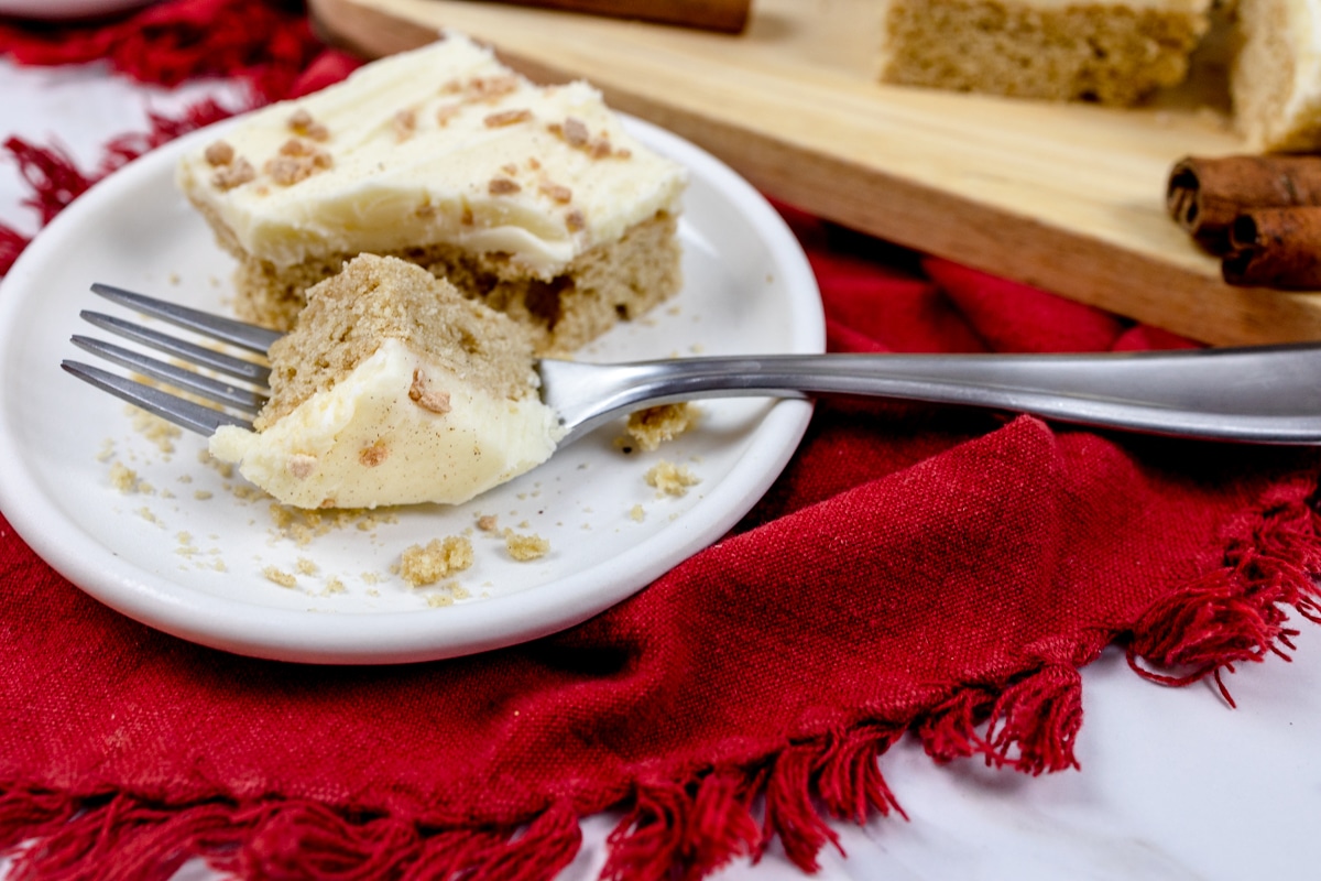 Close up of an eggnog cookie bar on a plate with a fork cutting into it. 