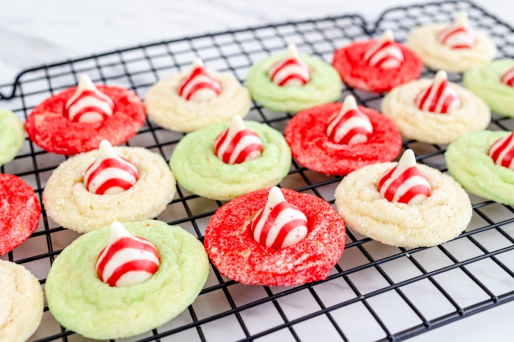 Close up of sugar cookies with candy cane kisses on them on a wire rack.
