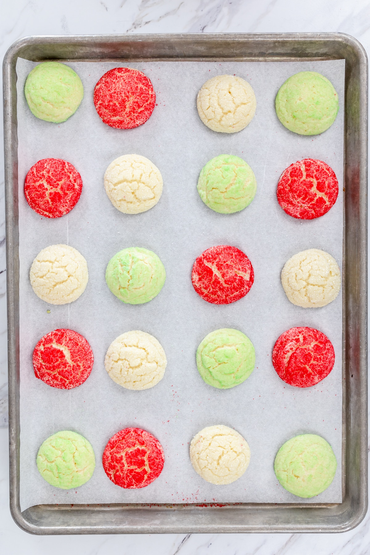 Top view of green, white, and red freshly baked sugar cookies on a tray.
