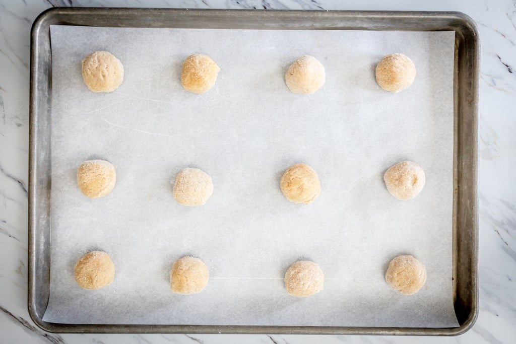 Top view of cookie dough balls on parchment paper on a baking tray.