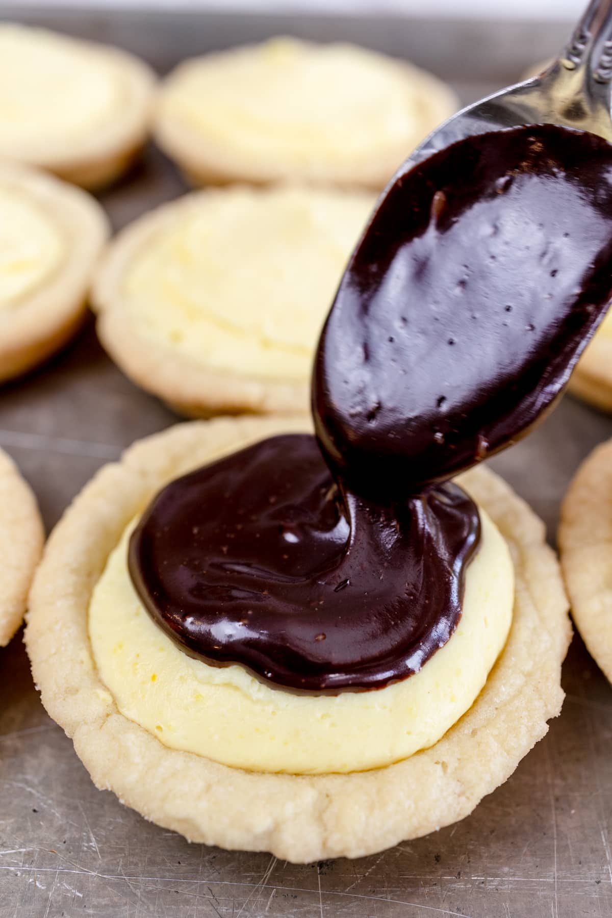 Close up of Boston cream pie cookie is topped with a tablespoon of chocolate ganache. 