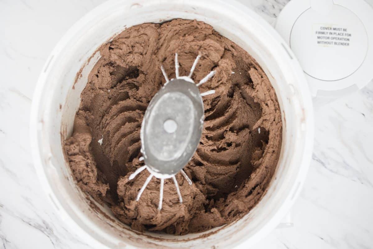 Top view of chocolate cookie dough being mixed in a stand mixer. 