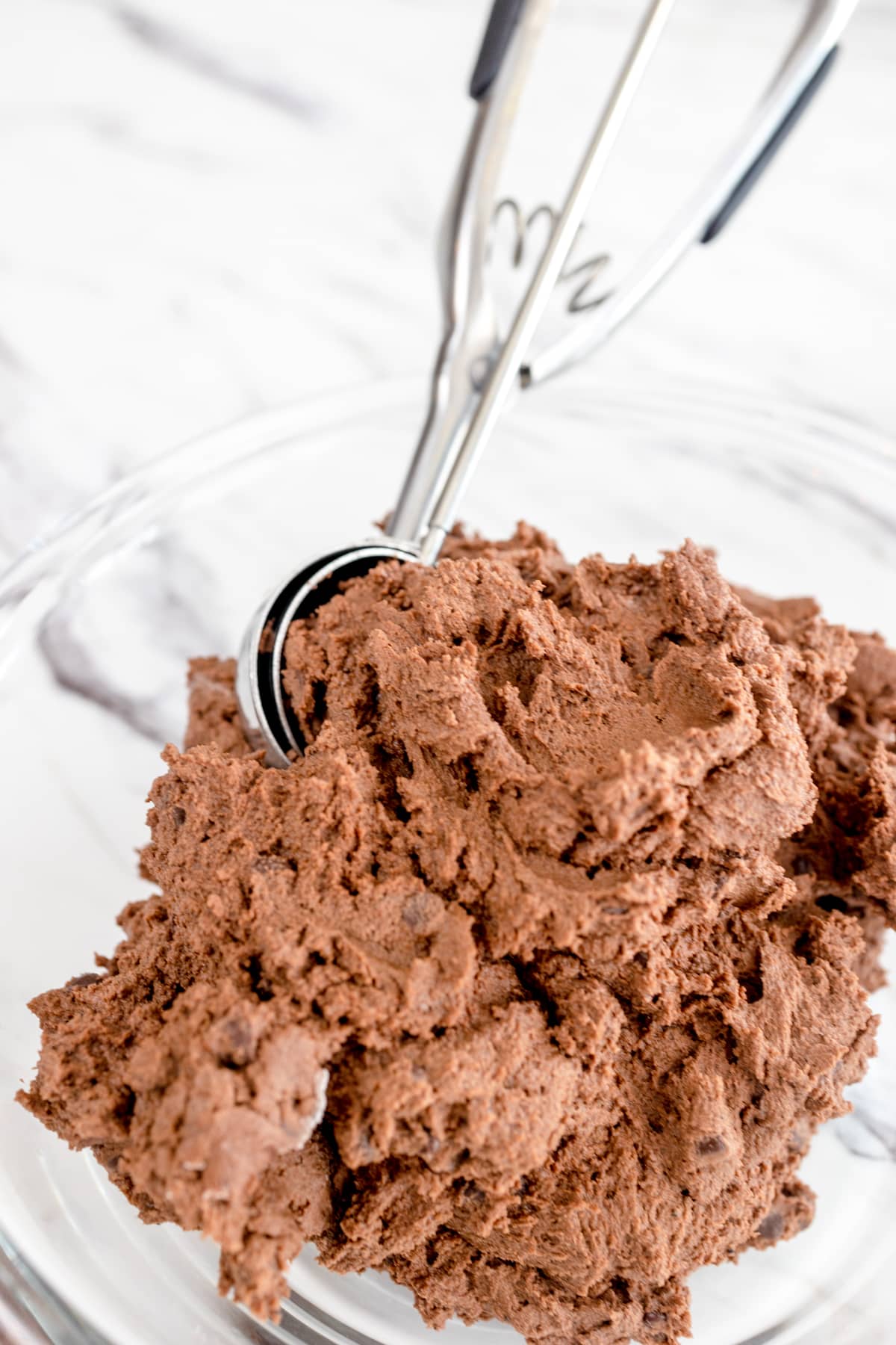 Close up of chocolate cookie dough being scooped by a cookie scoop. 