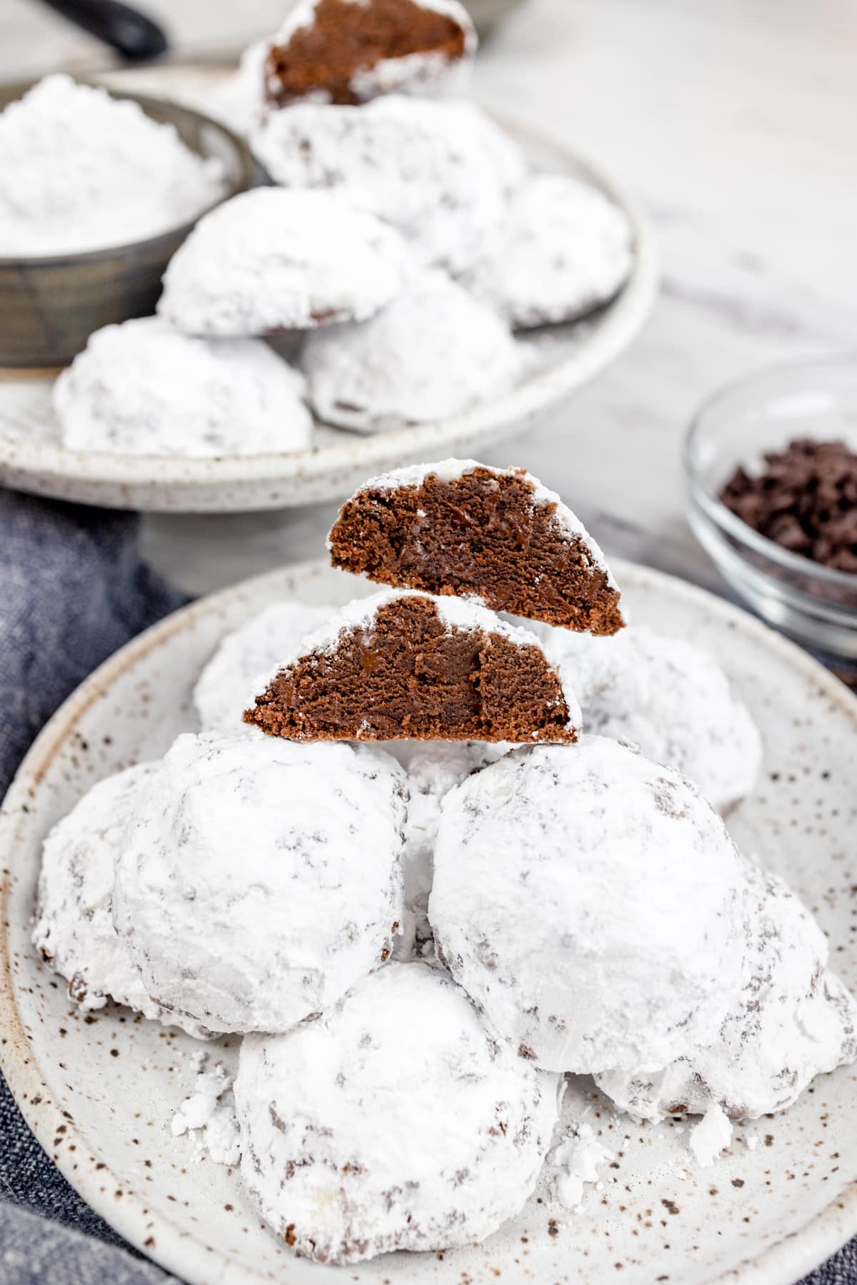 Chocolate Snowball Cookies stacked on a white plate. 