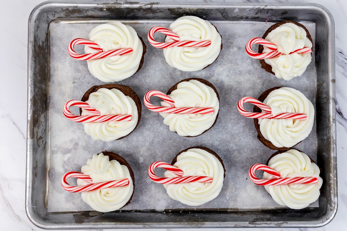 Top view of a tray with cookies on it that have frosting and a candy cane on them.