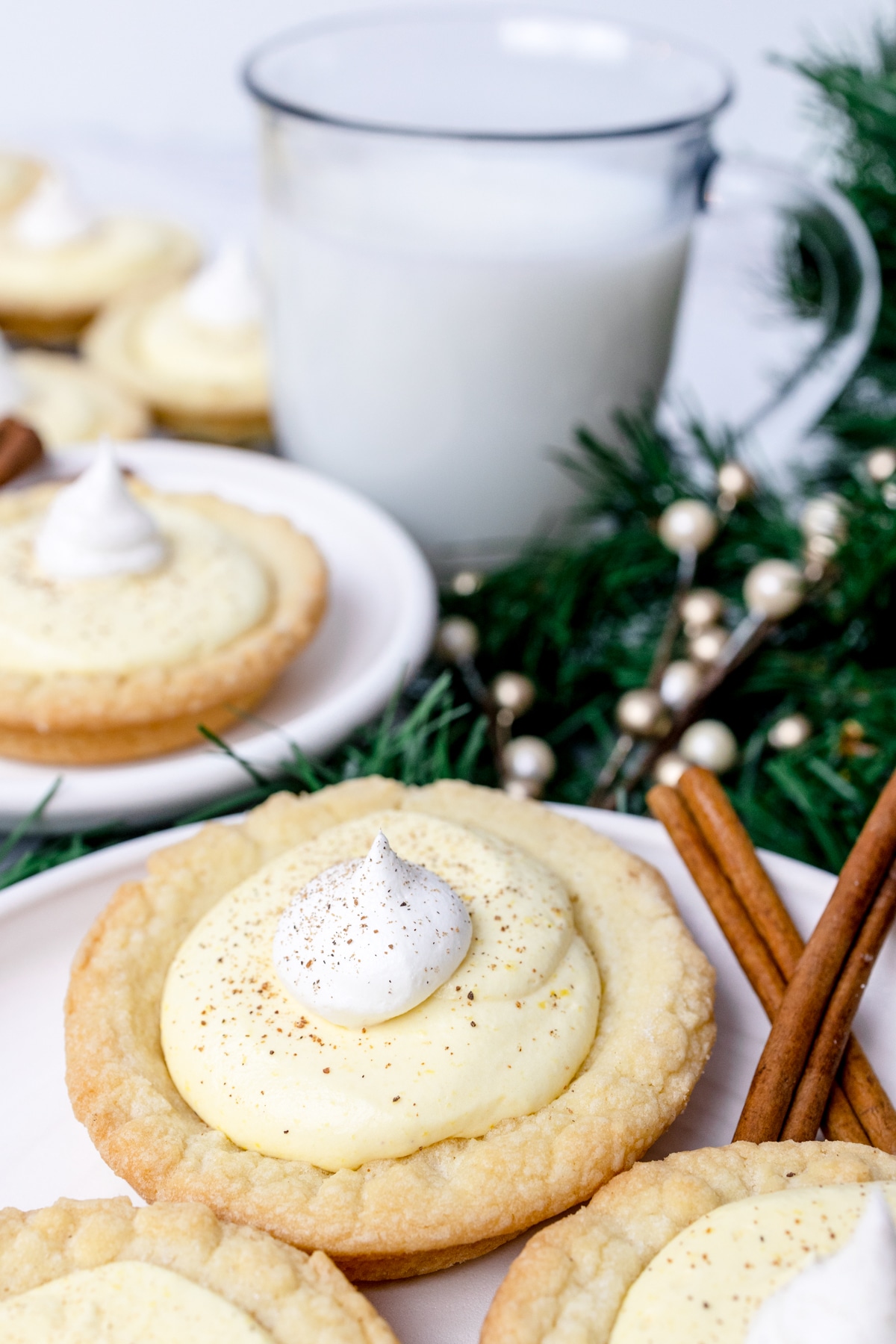 Close up of eggnog pie cookies on a plate with a glass of milk in the background. 