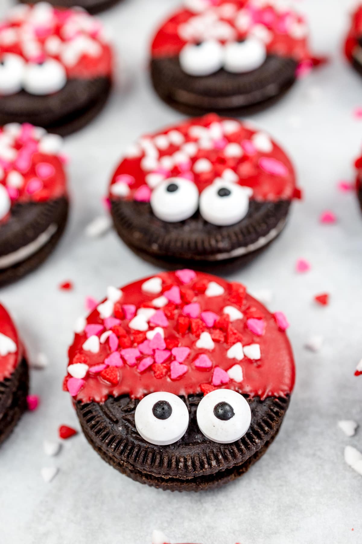 Close up of Love Bug Oreo cookies on parchment paper on a baking tray.