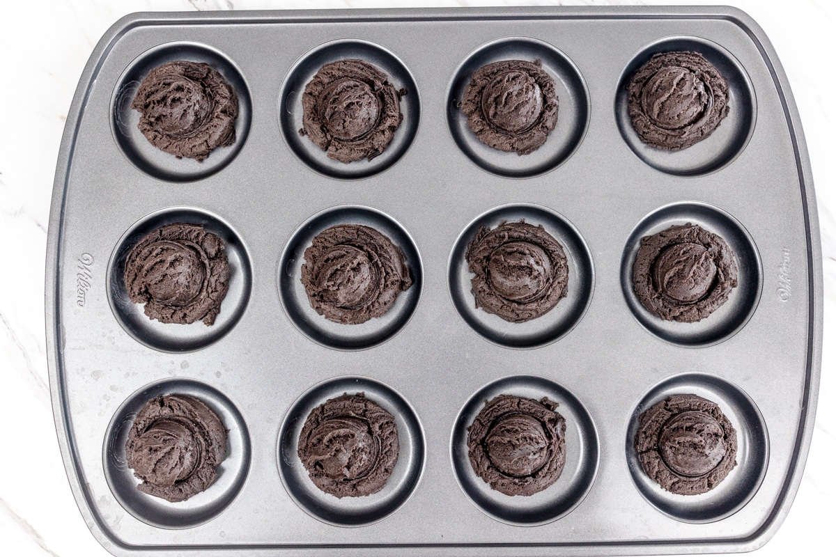 Top view of chocolate cookie dough balls in a muffin top pan.