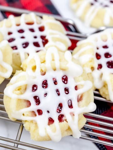 Close up of ClassicRaspberry Thumbprint Cookies on a wire rack.