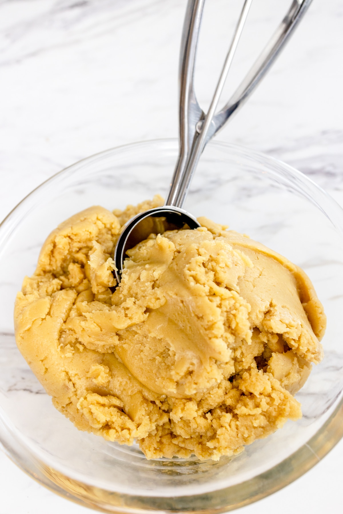 Top view of salted caramel cookie dough with a cookie dough scoop in the dough. 