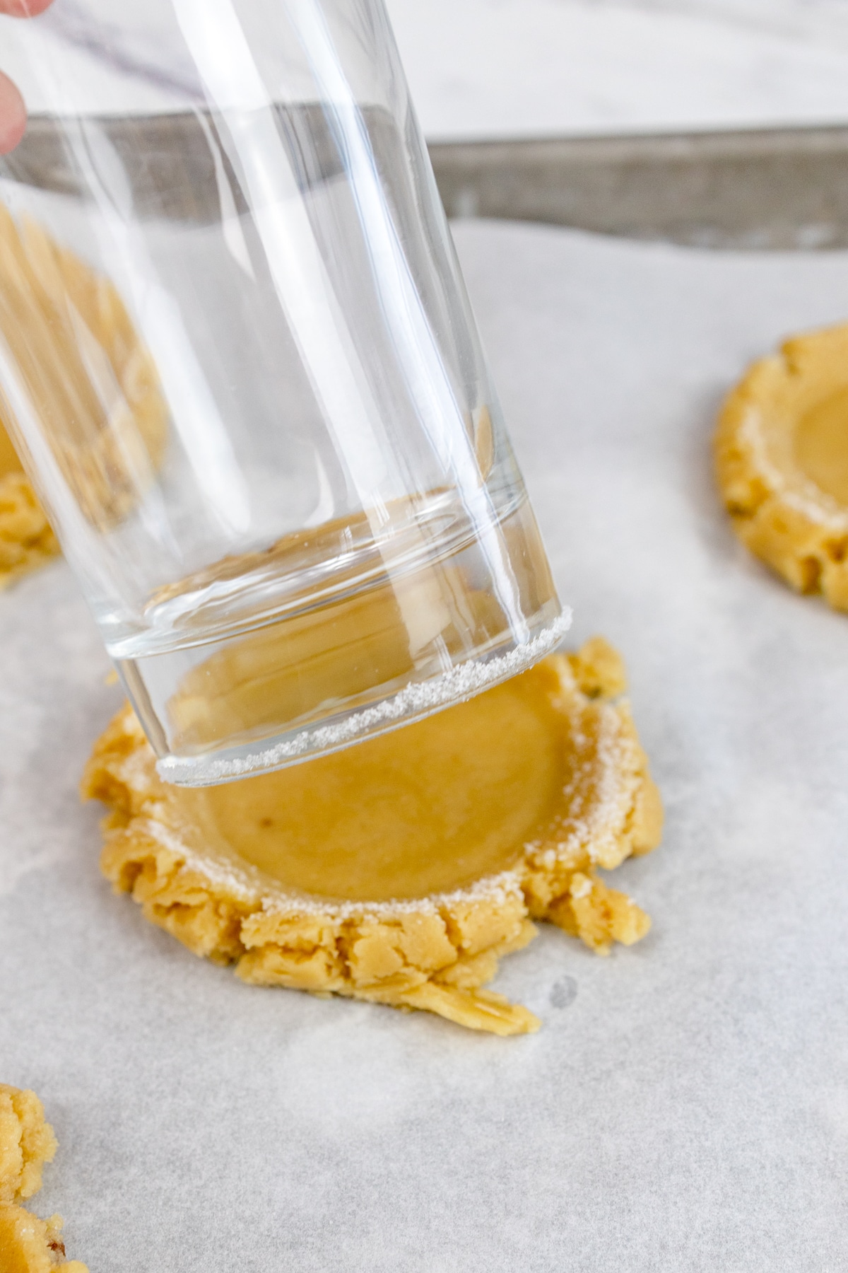 Close up of salted caramel cookie dough being flattened by a glass with a sugared bottom.