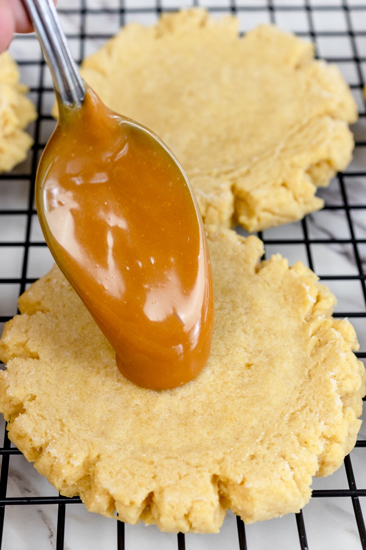 Close up of caramel topping being added to the top of cookies. 