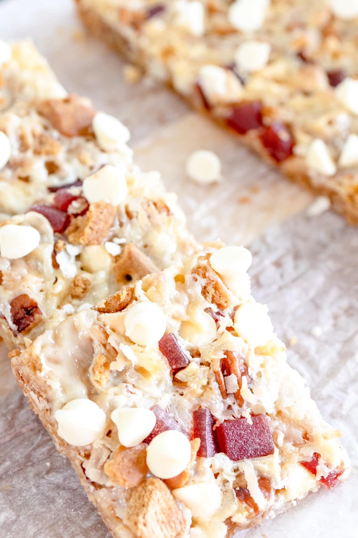Close up of strawberry magic bars in a line on parchment paper. 