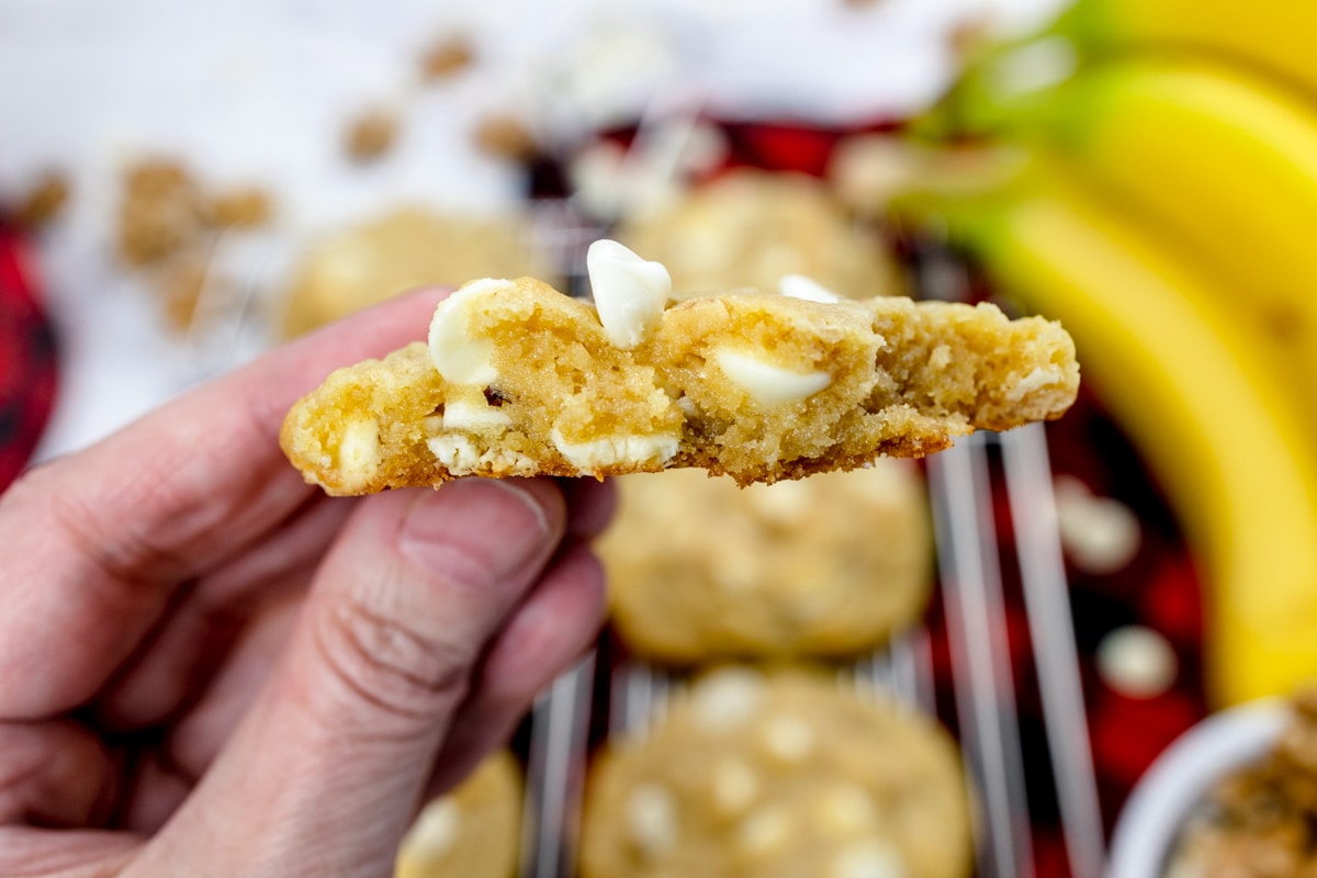 Close up of a banana pudding cookie being held up midair to show it's soft center.