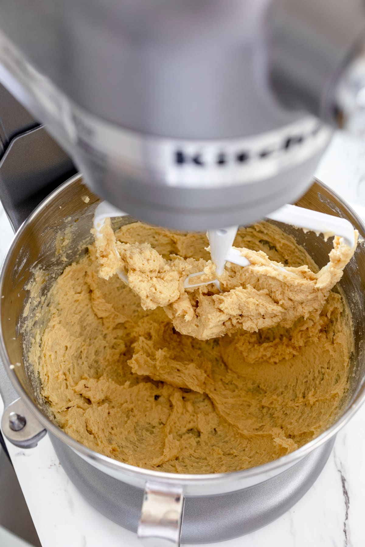 Close-up of a stand mixer with cookie dough being mixed in it. 