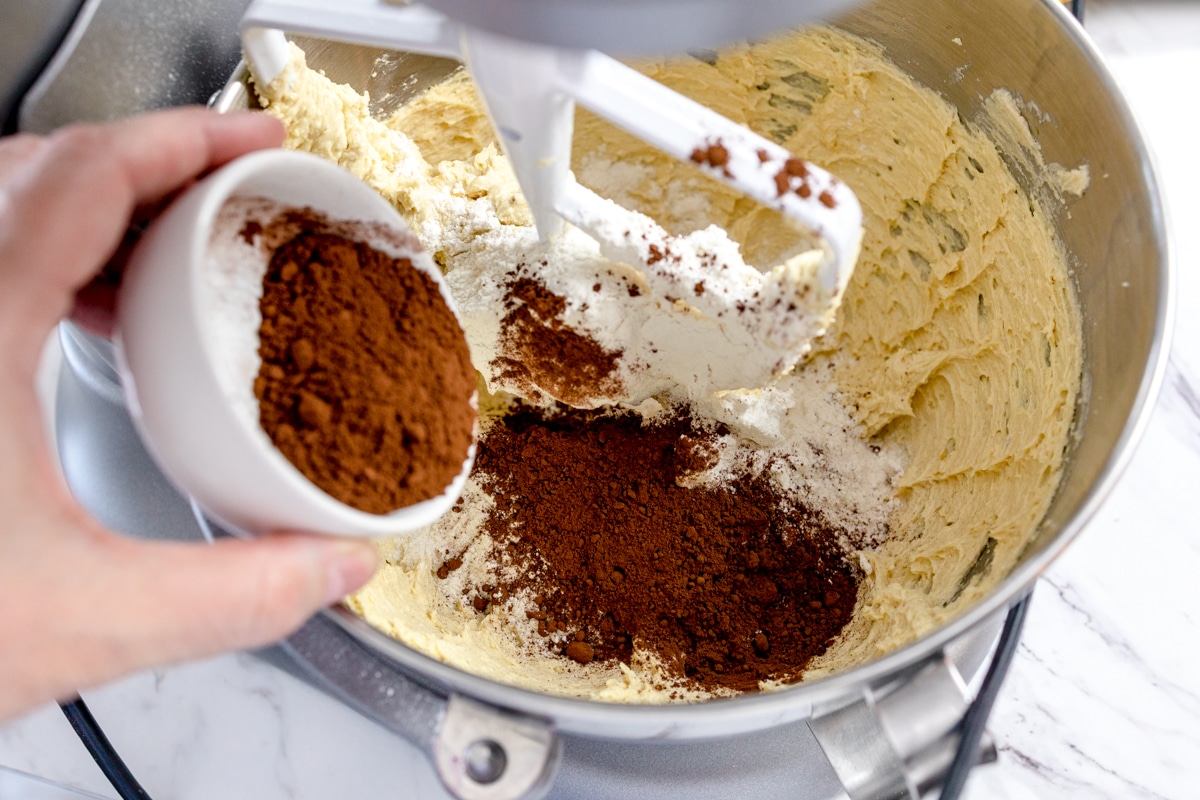 Close-up of stand mixer with cocoa powder being added to cookie dough. 