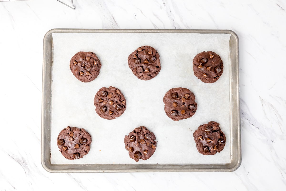 Top view of freshly baked chocolate pudding cookies on a baking tray lined with parchment paper. 
