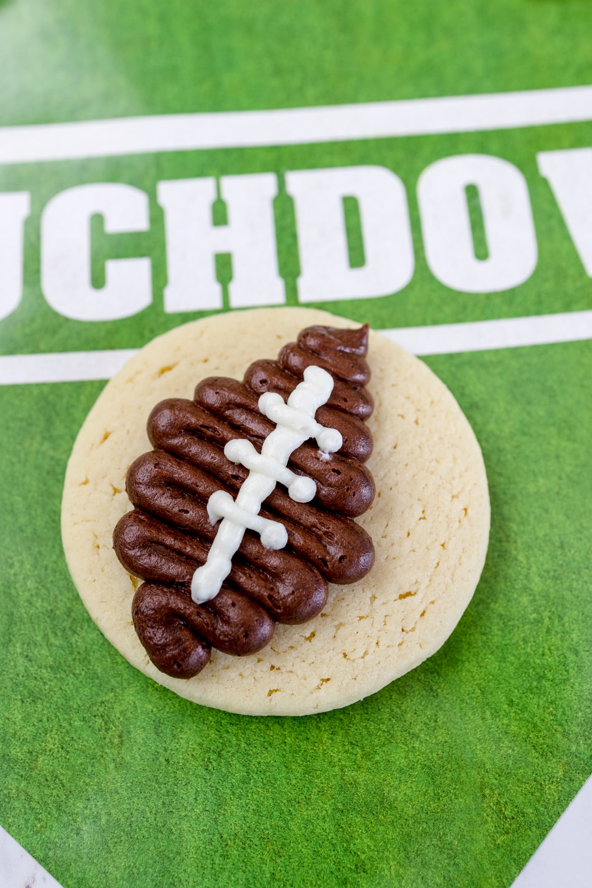 Top view of a round sugar cookie with a football frosted in the center. 