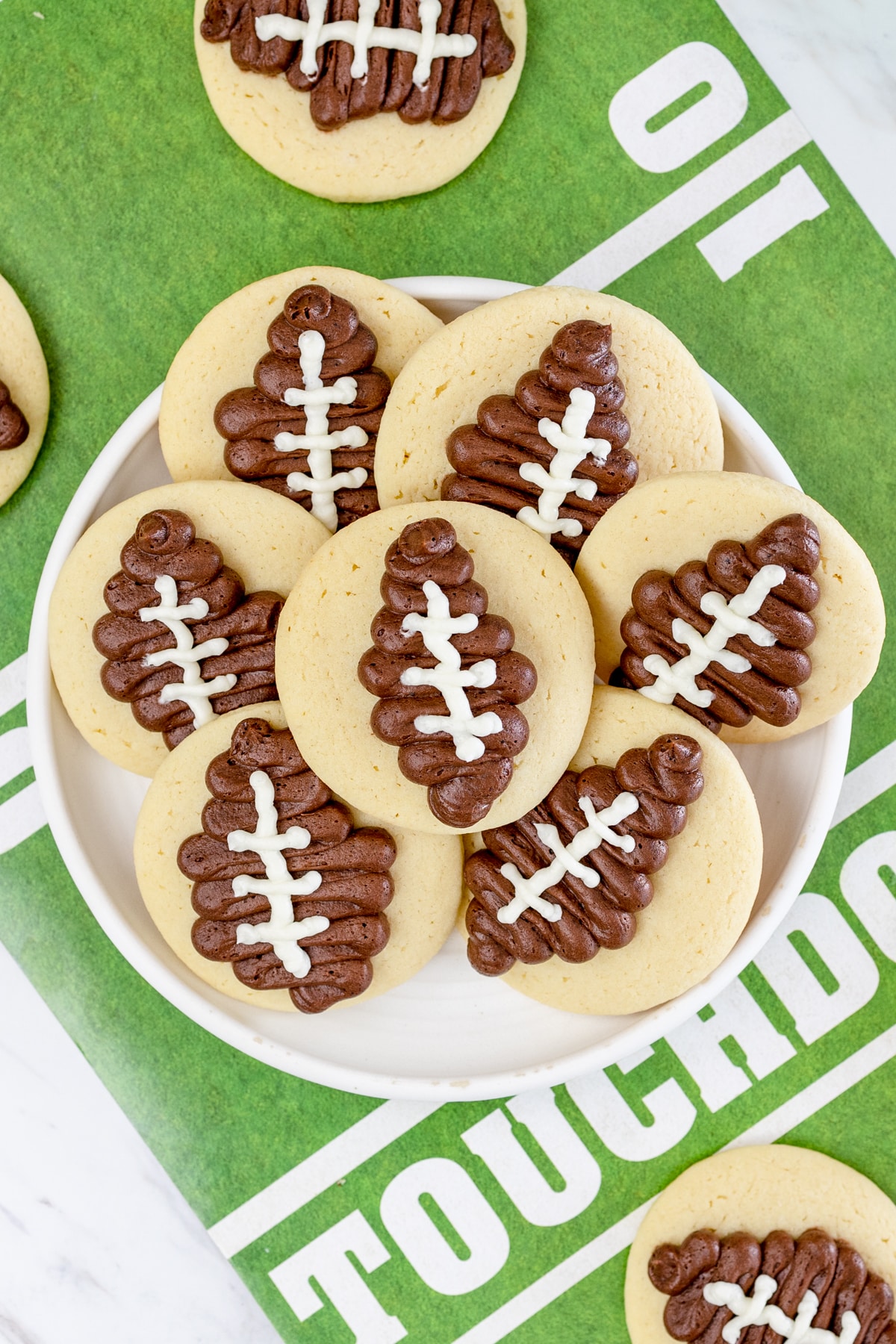 Top view of football sugar cookies on a white plate. 