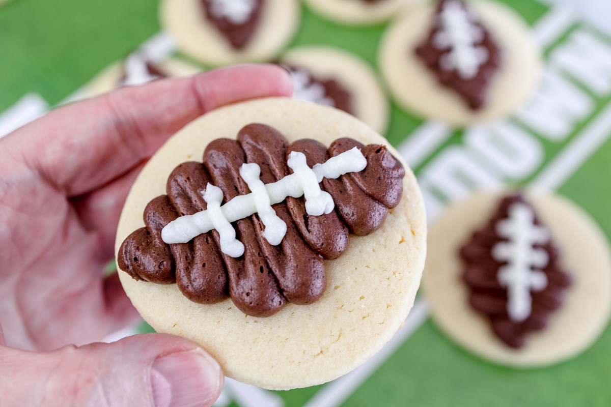 Close up of someone holding up a football sugar cookie. 
