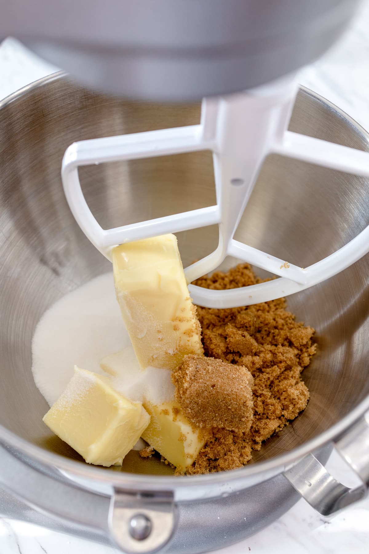 Close up of a stand mixer with butter and sugar being mixed in the bowl. 