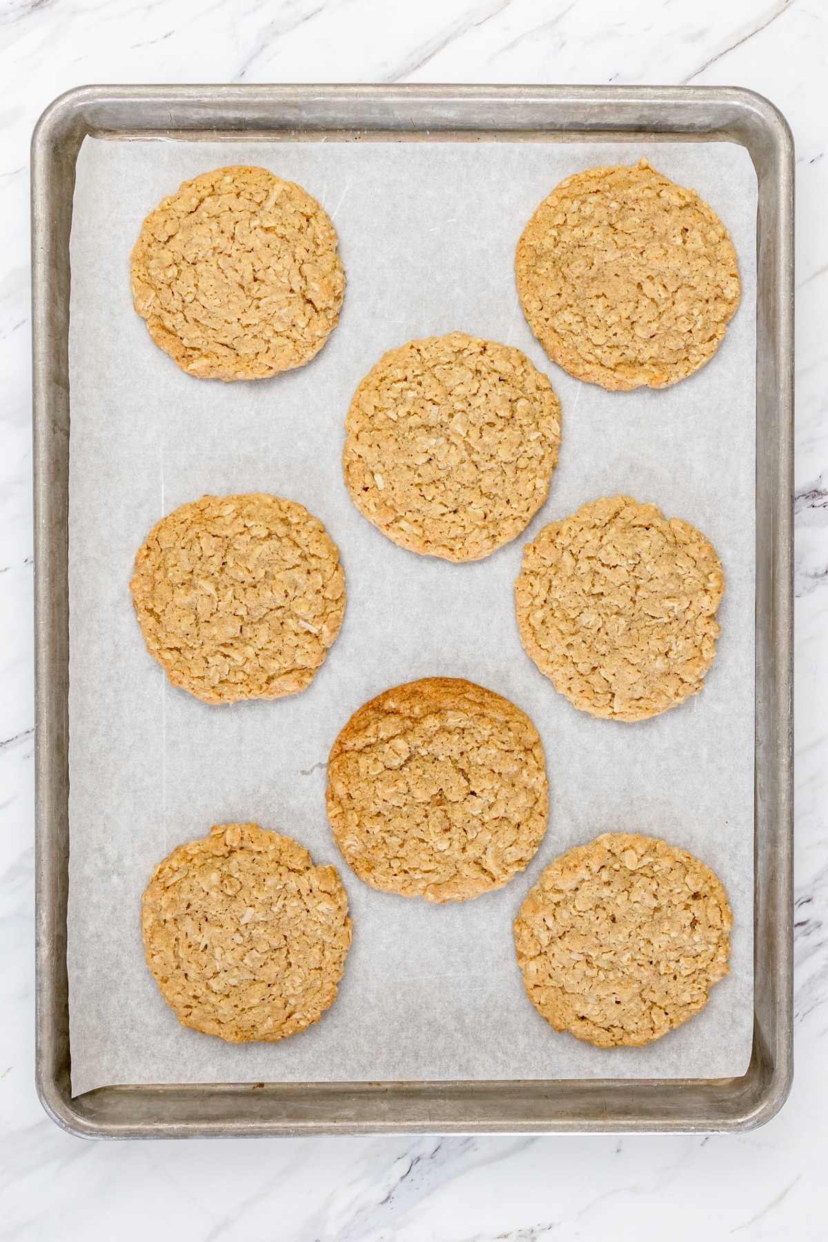 Top view of baked oatmeal coconut cookies on a cookie tray. 