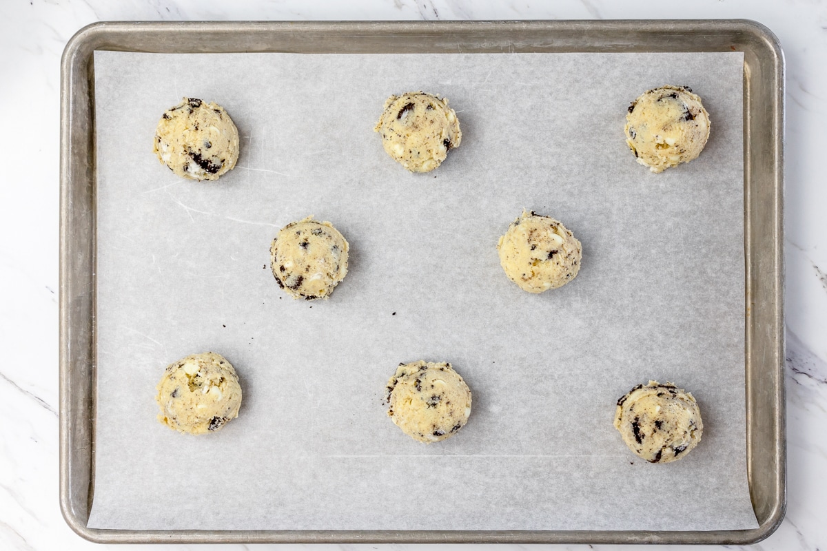 Top view of Oreo cheesecake cookie dough balls on a baking sheet lined with parchment paper. 