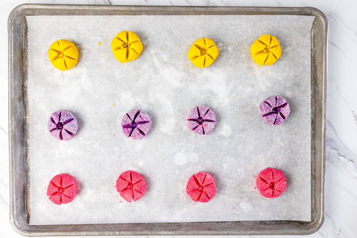 Top view of colorful unbaked cookies on a baking tray on parchment paper. 