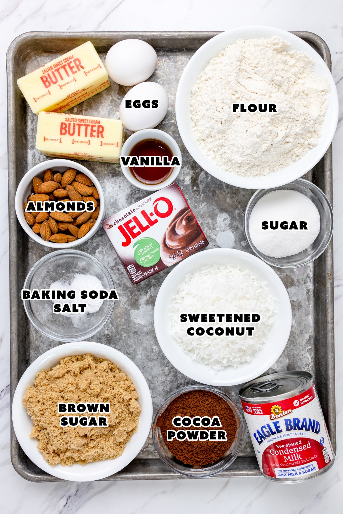 Top view of ingredients needed to make Almond Joy Cookies in small bowls on a baking tray. 