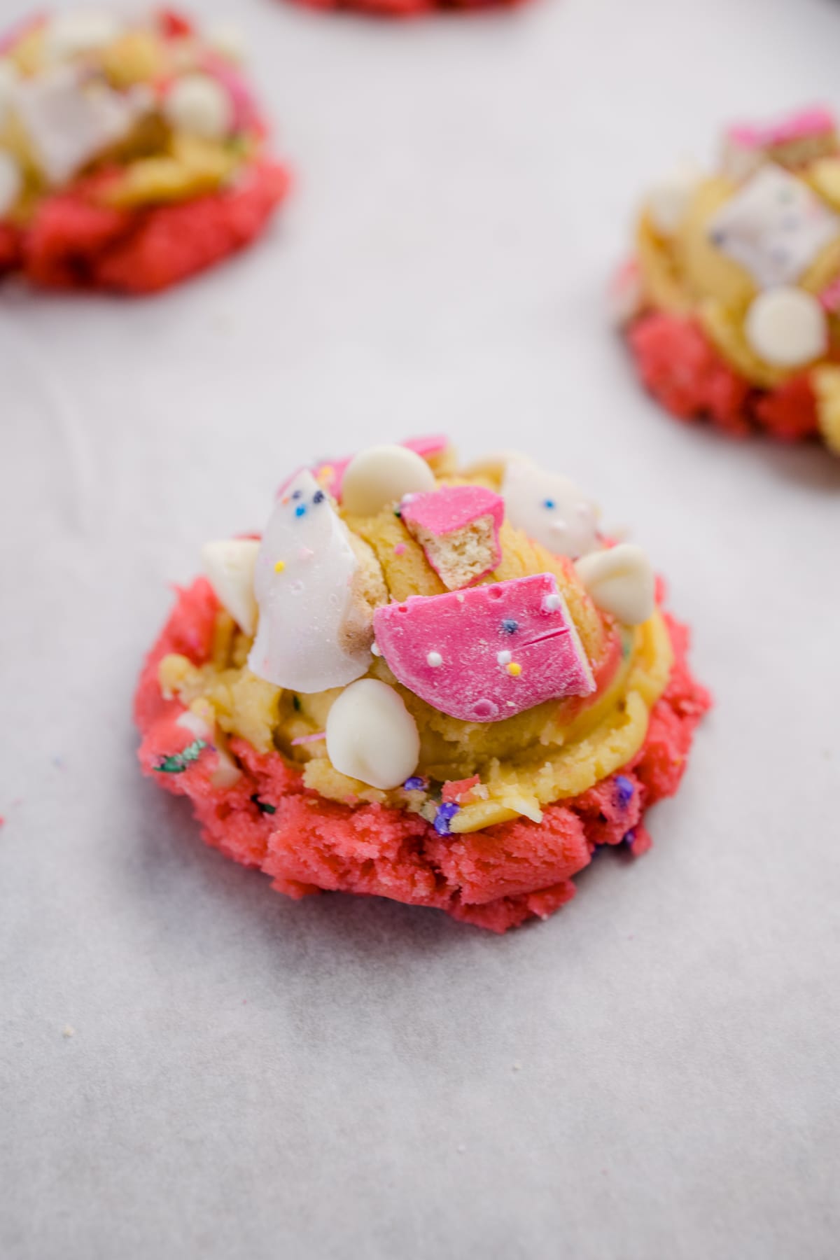 Close up of a circus animal cookie dough ball on a baking tray with extra circus animal cookie pieces on top. 
