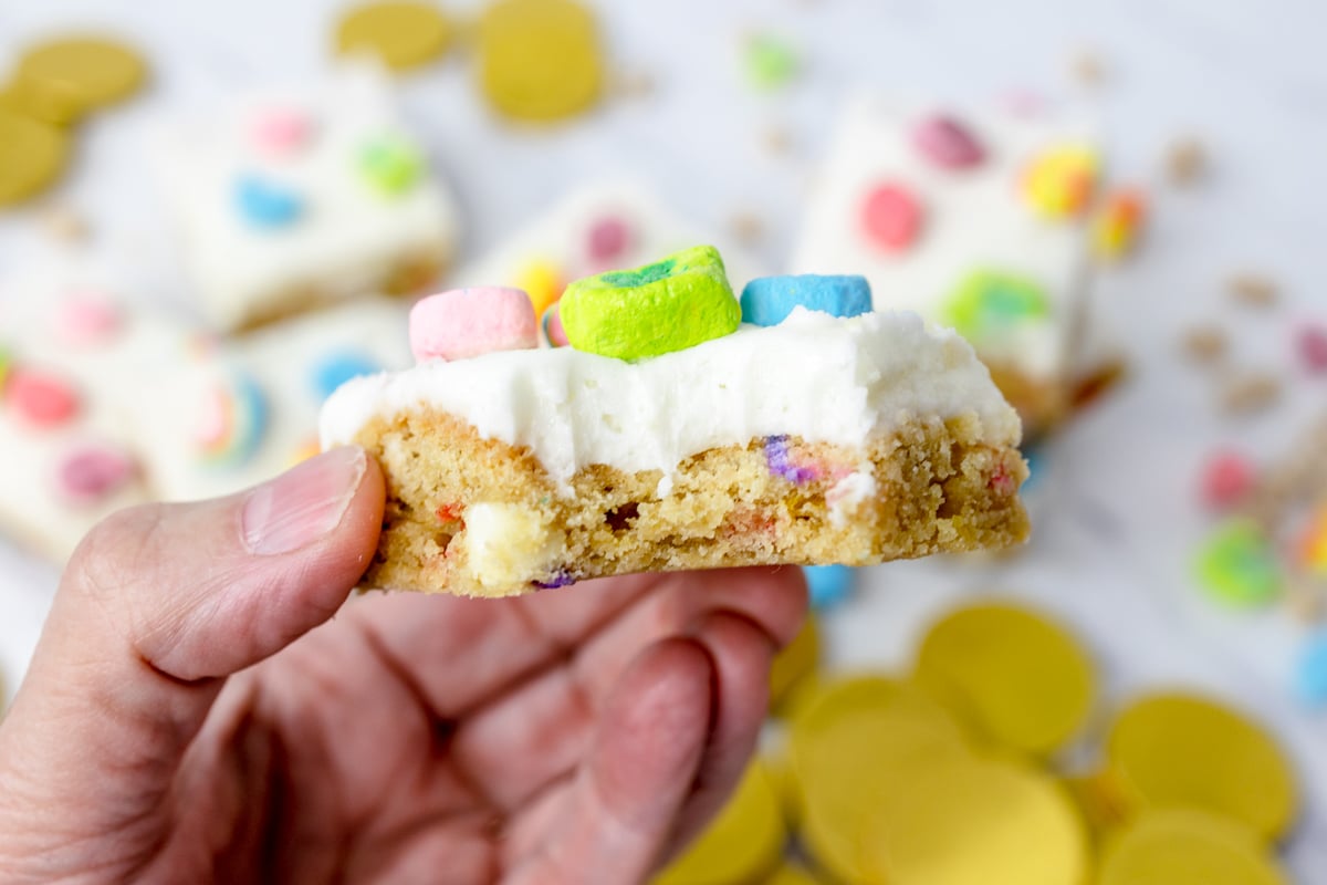 Close up of a lucky charms bar being held in mid-air with a bite taken out of it. 