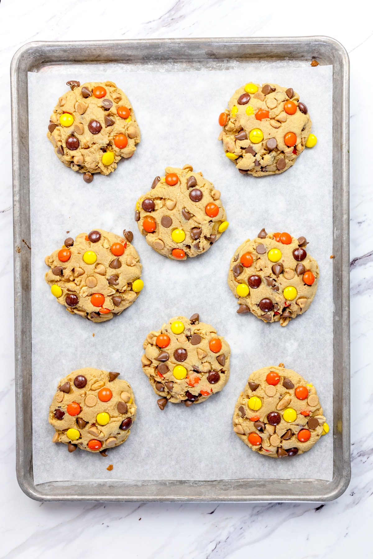 Top view of medium reeces pieces cookies on a baking tray.