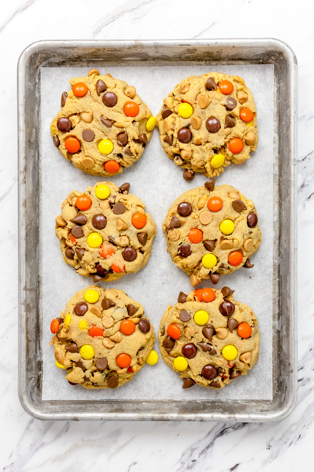 Top view of large reeces pieces cookies on a baking tray.