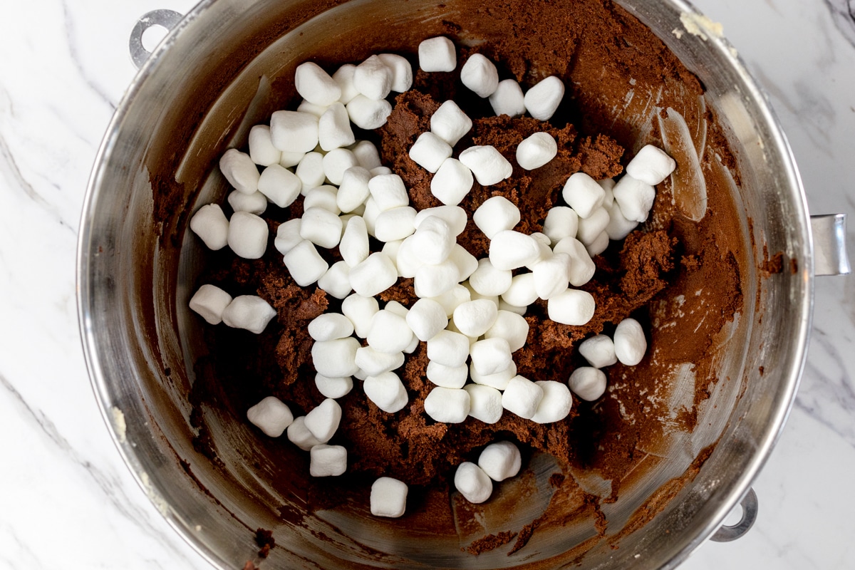 Top view of mixing bowl with chocolate cookie dough in it and marshmallows on top. 