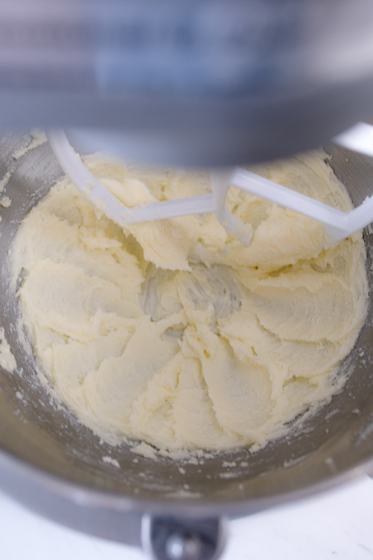 Close up of a stand mixer creaming butter and sugar together with a paddle attachment. 