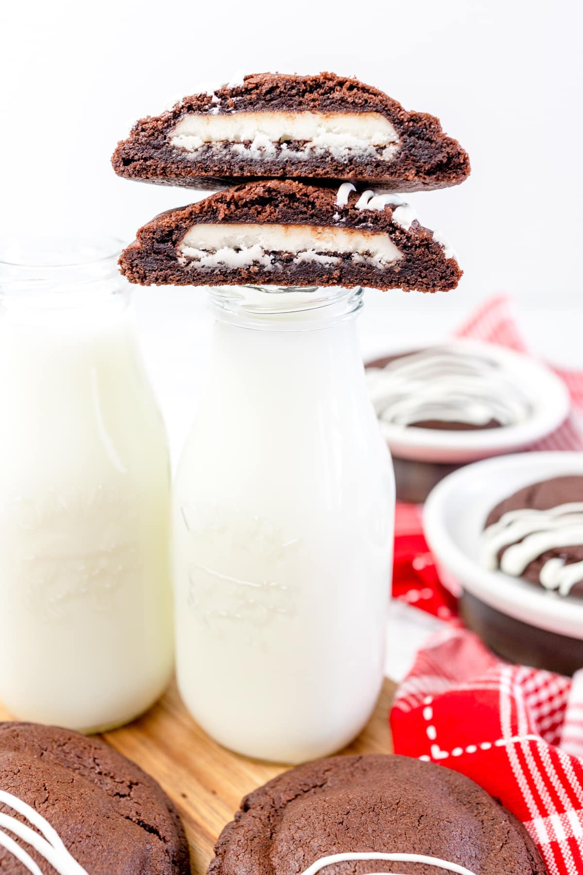 Close up of a glass bottle of milk with a peppermint patty cookie halved on top so you can see the peppermint patty inside. 