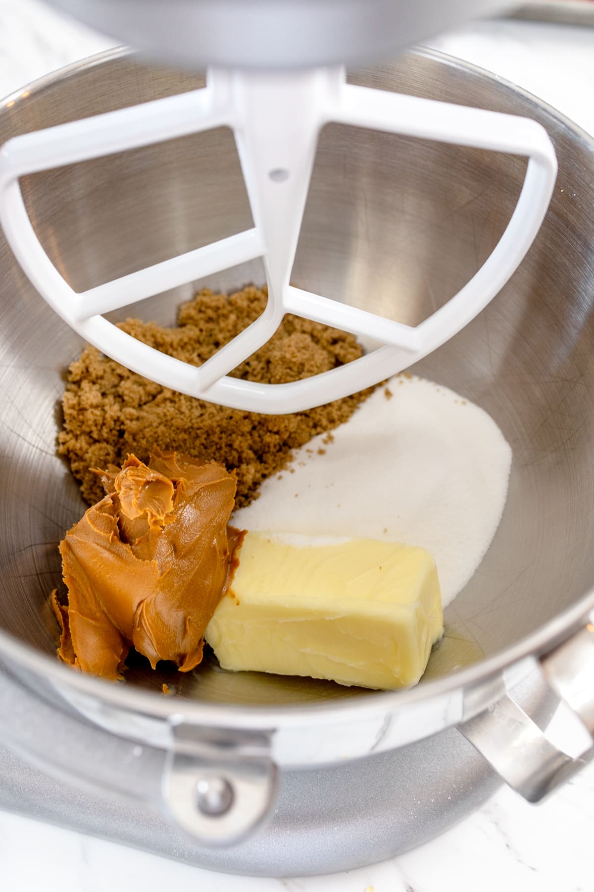Close up of a stand mixer with a paddle attachment about to cream butter and sugars. 