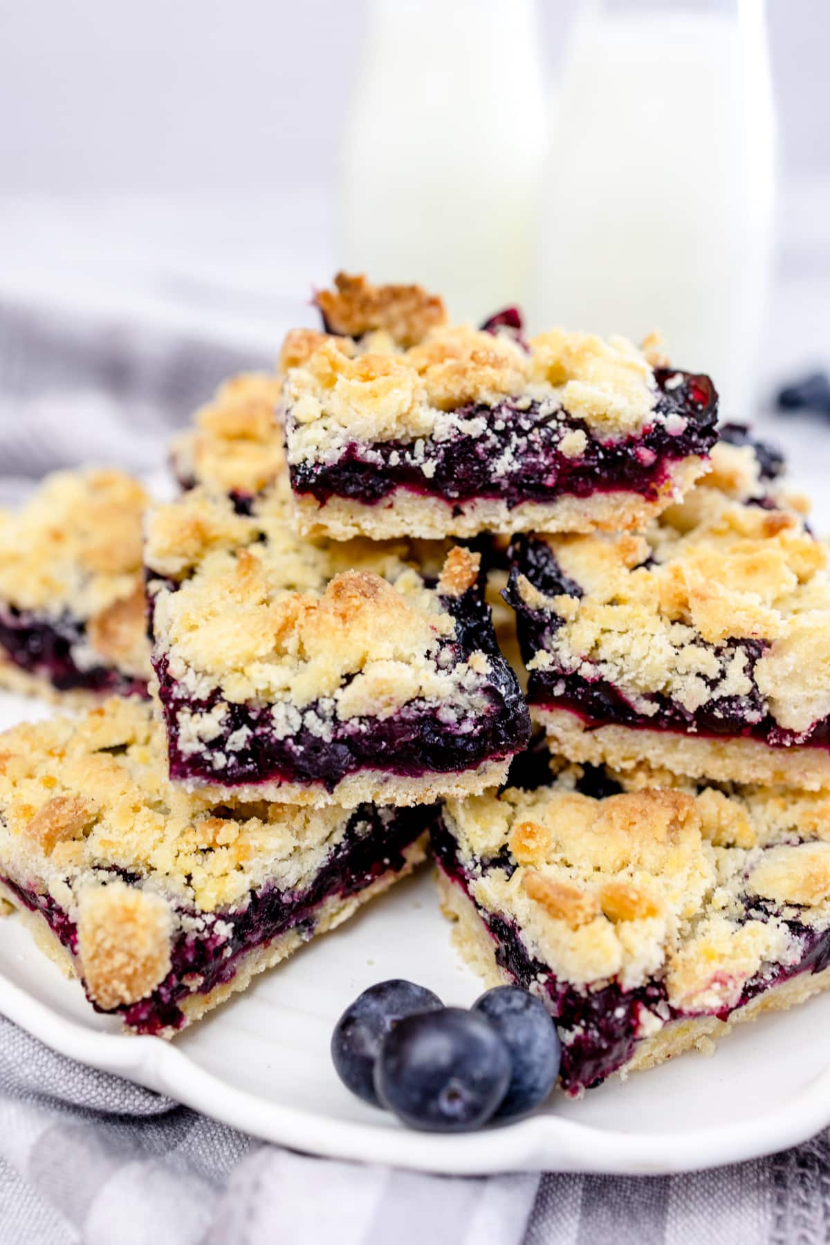 Close up of blueberry pie bars stacked on a white plate.