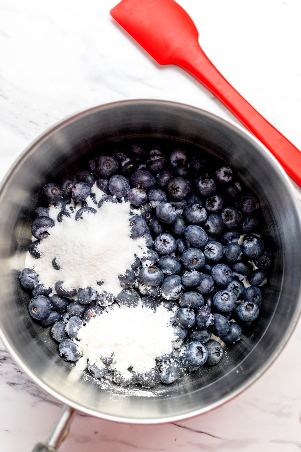 Top view of fresh blueberries in a pot with sugar on top. 