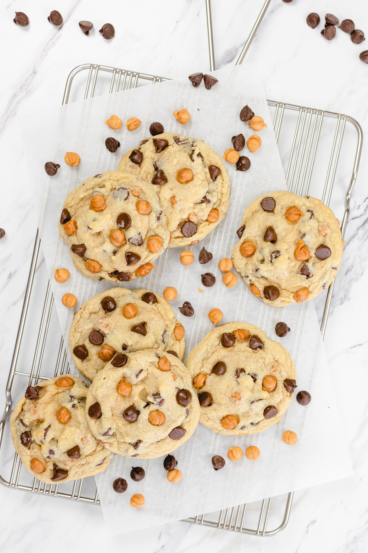 Top view of Caramel Chocolate Chip Cookies on a wire rack with caramel chips and chocolate chips dotted around them.